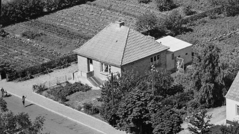 Niels Ejnar Kjær ejede huset fra 1958 til 1973. Det kunne være Else Kjær i hønsehuset og børnene på vejen.
1958 Sylvest Jensen Luftfoto; Det Kgl. Bibliotek.
http://www5.kb.dk/danmarksetfraluften/images/luftfo/2011/maj/luftfoto/object1781677